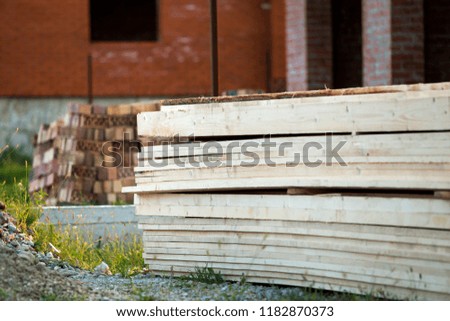 Stack of natural brown uneven rough wooden boards on building site. Industrial timber for carpentry, building, repairing and furniture, lumber material for roofing construction.