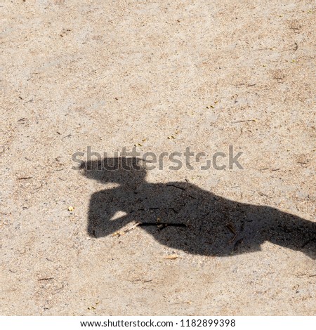 Instagram size photo of shadow of teenage girl on rough sand, on sunny day.