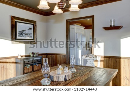 Rustic dining room design showcases half wood paneling on the walls. Northwest, USA, 