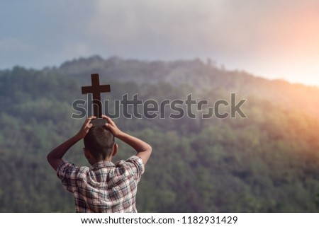 Boy raised the cross of christian overhead