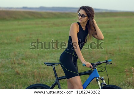 Girl on a mountain bike on offroad, beautiful portrait of a cyclist at sunset