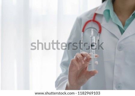 Young female doctor holding a syringe.