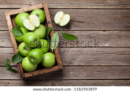 Ripe green apples box on wooden table. Top view with space for your text