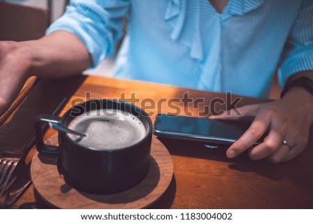 Woman using smartphone with a black coffee on beside