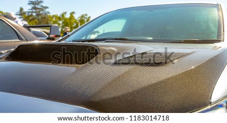Carbon fiber hood of a silver car on a sunny day