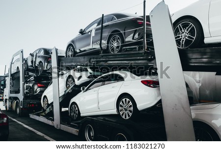 Big car carrier truck of new luxury sport  german cars for batch delivery to dealership . Full load transport truck of new powerful new vehicles. Automotive industry  rent  shipping background. Royalty-Free Stock Photo #1183021270