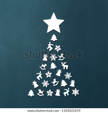 Christmas card with place for your text. A large Christmas tree on a dark background, lined with white wooden figures in the form of snowflakes, a Christmas tree, a horse, a deer, a bell. White Star