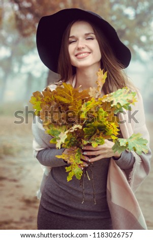 A beautiful girl in hat walks on the autumn forest