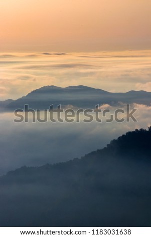 Telephoto-panoramic landscape above clouds with mountains peaks.