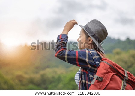 Young traveler woman in hipster style with backpack and hat standing looking the sky