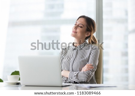 Smiling businesswoman sitting in office chair relaxing with eyes closed, calm female worker or woman ceo feeling peaceful resting at workplace dreaming about positive things distracted from work Royalty-Free Stock Photo #1183089466