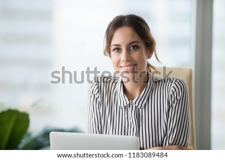 Close up portrait of smiling beautiful millennial businesswoman or CEO looking at camera, happy female boss posing making headshot picture for company photoshoot, confident successful woman at work Royalty-Free Stock Photo #1183089484