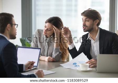 Male colleagues argue having dispute at company briefing, woman worker stay calm and peaceful managing stress distracted form conflict, managers or partners disagree on terms at meeting Royalty-Free Stock Photo #1183089529