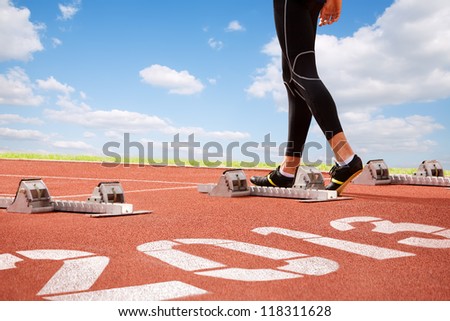 Workout of athlete on start line of cinder-track with numerals of new year on sky background. Royalty-Free Stock Photo #118311628