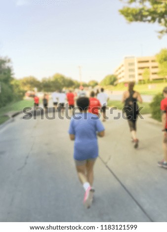 Motion blurred group runners of all abilities at 5K Corporate Challenge race in Richardson, Texas, US. Fitness and healthy lifestyle concept. Athletes running on the roads. Urban sport event abstract