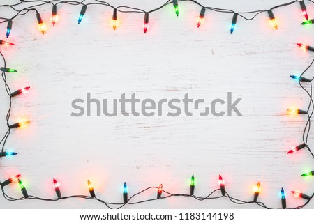 Christmas lights bulb frame decoration on white wood. Merry Christmas and New Year holiday background. top view