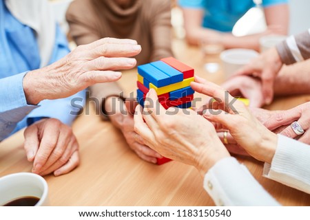 Group seniors with dementia builds a tower in the nursing home from colorful building blocks Royalty-Free Stock Photo #1183150540