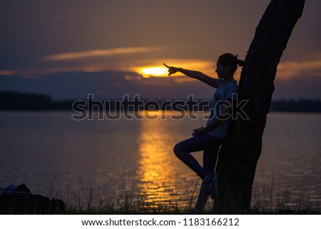 Alone girl standing and hand pointer on silhouette sunset at river side.
