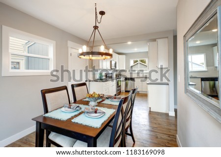 Light gray interior of transitional dining room and white kitchen at the background.