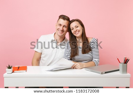 Two young tender business woman man colleagues sit work at white desk with contemporary laptop isolated on pastel pink background. Achievement career concept. Copy space advertising, youth co working