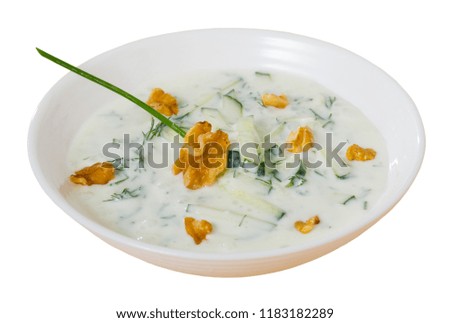 Bulgarian cuisine. Traditional chilled soup Tarator on yogurt with fresh cucumber, dill and walnuts in white plate. Isolated over white background