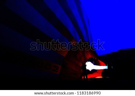 Preparation balloon, night dark blue sky in dawn, man preparing fire from gas put in to Balloon, closeup and silhouette picture, technology for travel at Cappadocia Turkey concept  