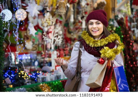 Portrait of beautiful brunette girl choosing Christmas decoration at market
