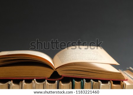 Open book on black background, hardback books on wooden table. Education and learning background. Back to school, studying. Copy space for text