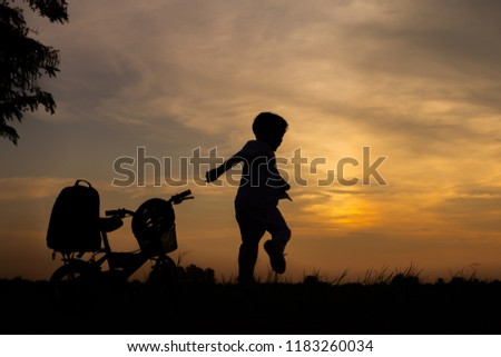 Silhouette of happy children with bicycle playing at sunset
