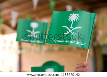 Miniature National Day of Saudi Arabia icon flag with phrase translated: Kingdom of Saudi Arabia. Isolated from blur student background.