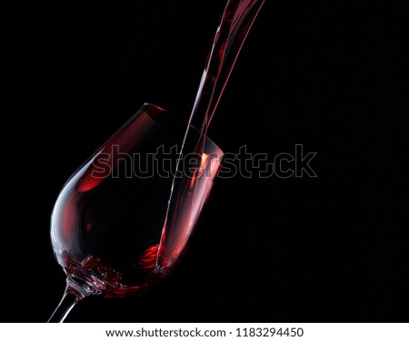 A bottle of red wine and a glass with red wine