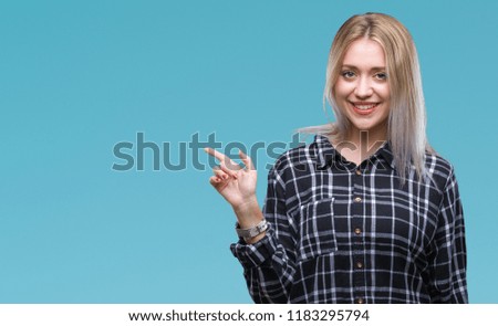 Young blonde woman over isolated background with a big smile on face, pointing with hand and finger to the side looking at the camera.