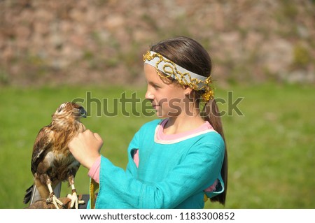 A young bird of prey sitting on the girl's hand in the spring .Falcon. Peregrine. Balaban