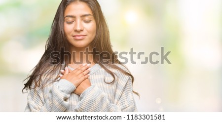Young beautiful arab woman wearing winter sweater over isolated background smiling with hands on chest with closed eyes and grateful gesture on face. Health concept. Royalty-Free Stock Photo #1183301581