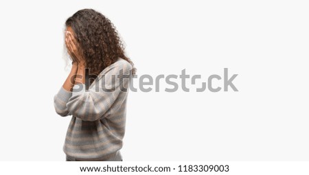Beautiful young hispanic woman wearing stripes sweater with sad expression covering face with hands while crying. Depression concept.