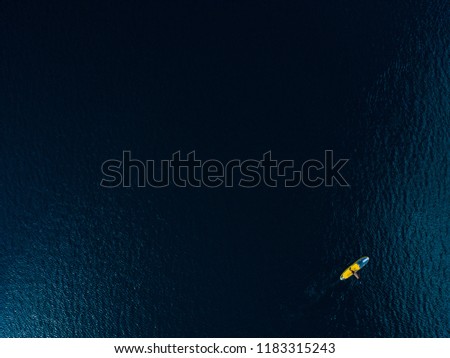 minimalist picture of a stand up paddler from above 