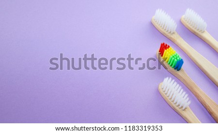 White and rainbow wooden toothbrushes on violet or purple background. Concept of racism, social exclusion, depression or loneliness, social problems or illegal migration
