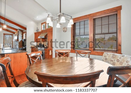 Dining area with round wooden table and vaulted ceiling.