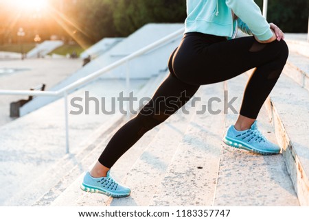 Cropped photo of amazing young sports woman in park outdoors make sport stretching exercises.