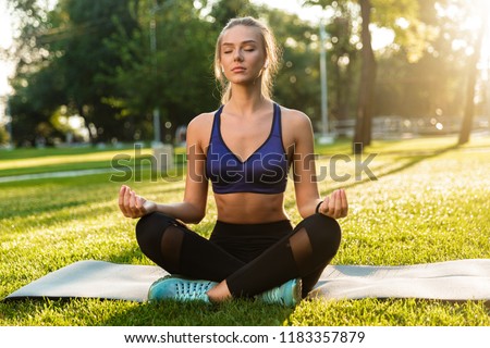 Photo of amazing concentrated young sports woman in park outdoors meditate.