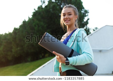 Photo of amazing happy young sports woman in park outdoors holding rug.