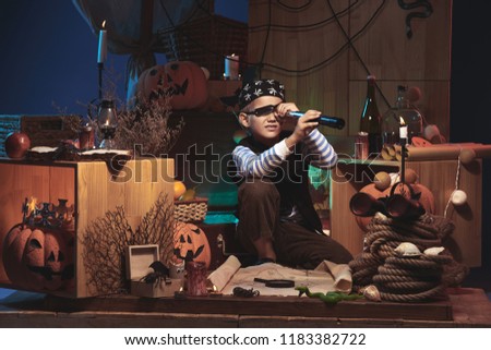 Boy in pirate costume looking through telescope on Halloween nigh