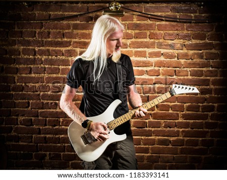 Young man with a blonde hair playing guitar in pub