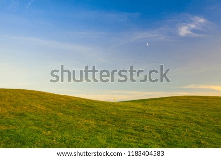 Golf field with yellow flag in the hole at sunset
