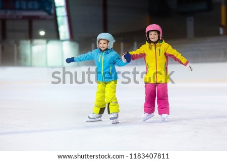 Children skating on indoor ice rink. Kids and family healthy winter sport. Boy and girl with ice skates. Active after school sports training for young child. Snow fun activity by cold weather.