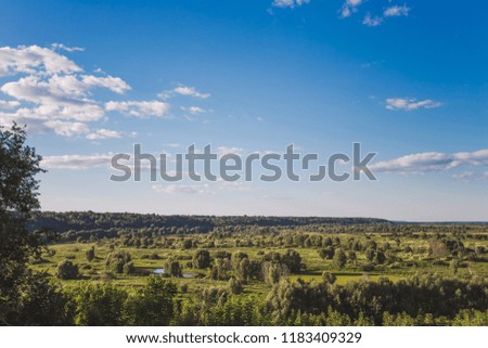 Beautiful green countryside landscape with charming calm blue sky with fluffy white clouds. Horizontal color photography.