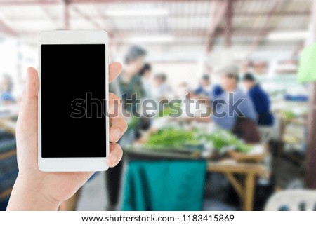 woman use mobile phone and blurred image of organic food market in thailand