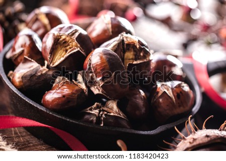 Roasted chestnuts served in a special perforated chestnut pan on an old wooden table