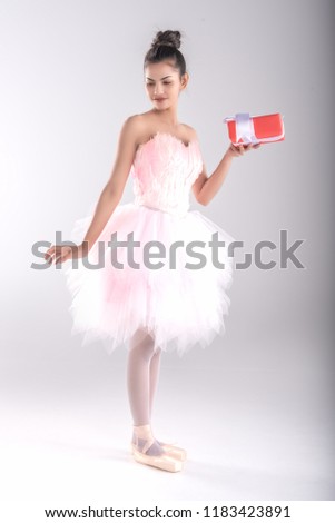 Beautiful young woman ballerina hold gife in hand for somebody special or in christmas and happy new year,show ballet dance,dress in pink feather,professional outfit,Beauty of classic ballet.
