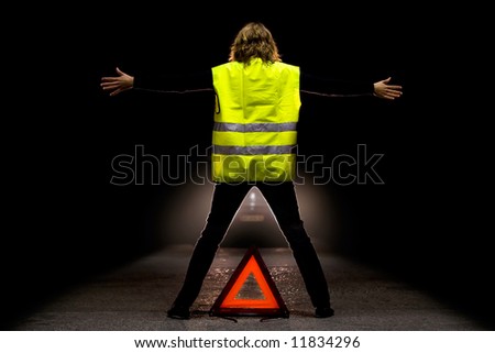 A girl wearing a fluo safety jacket trying to stop a car on a road at night. Royalty-Free Stock Photo #11834296